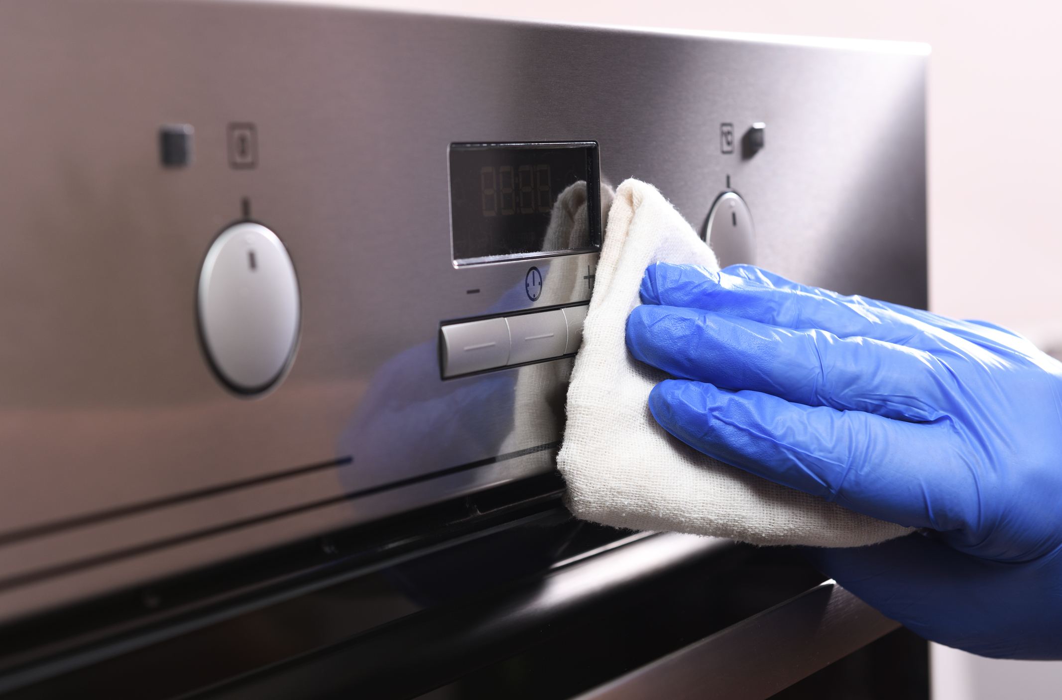 Cleaning the oven outside. A female hand in household cleaning gloves cleans the glass and the oven panel. Disinfection, fight against the virus, coronavirus. General or regular cleaning